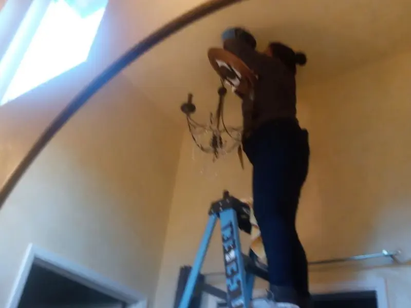 Electrician installing a chandelier in a Aloha residence
